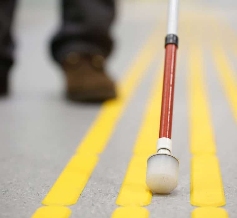 A person who is blind navigating a sidewalk