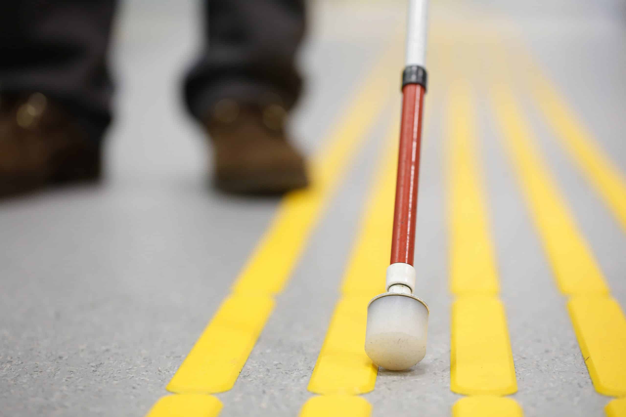 A person who is blind navigating a sidewalk