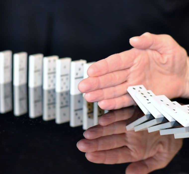 hand stopping falling dominos