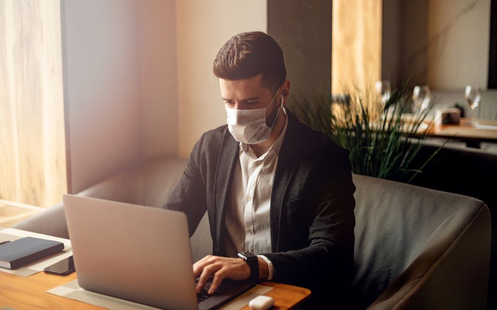 man working at computer wearing mask