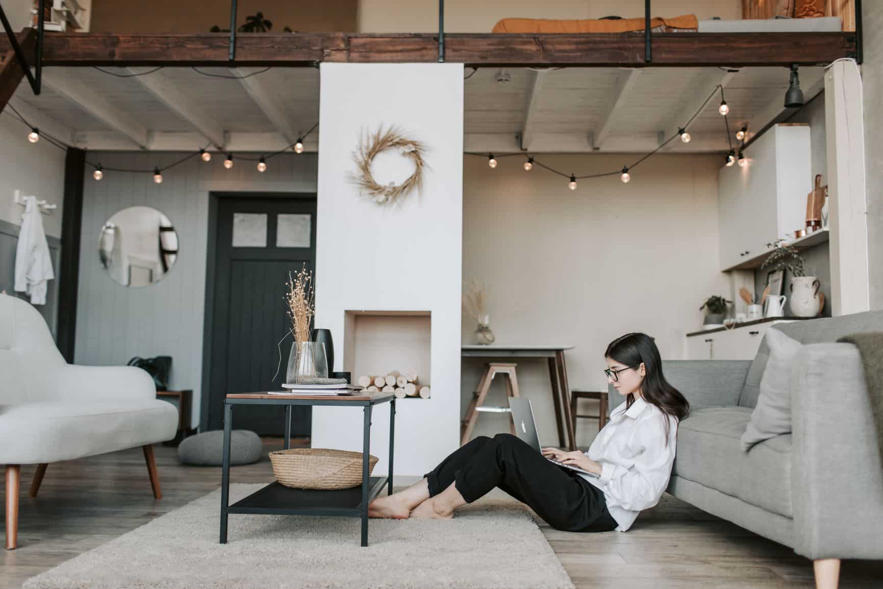 A woman sits on her floor at home on her laptop scrolling through social media and emails - during quarantine, it is a great time to do email marketing.