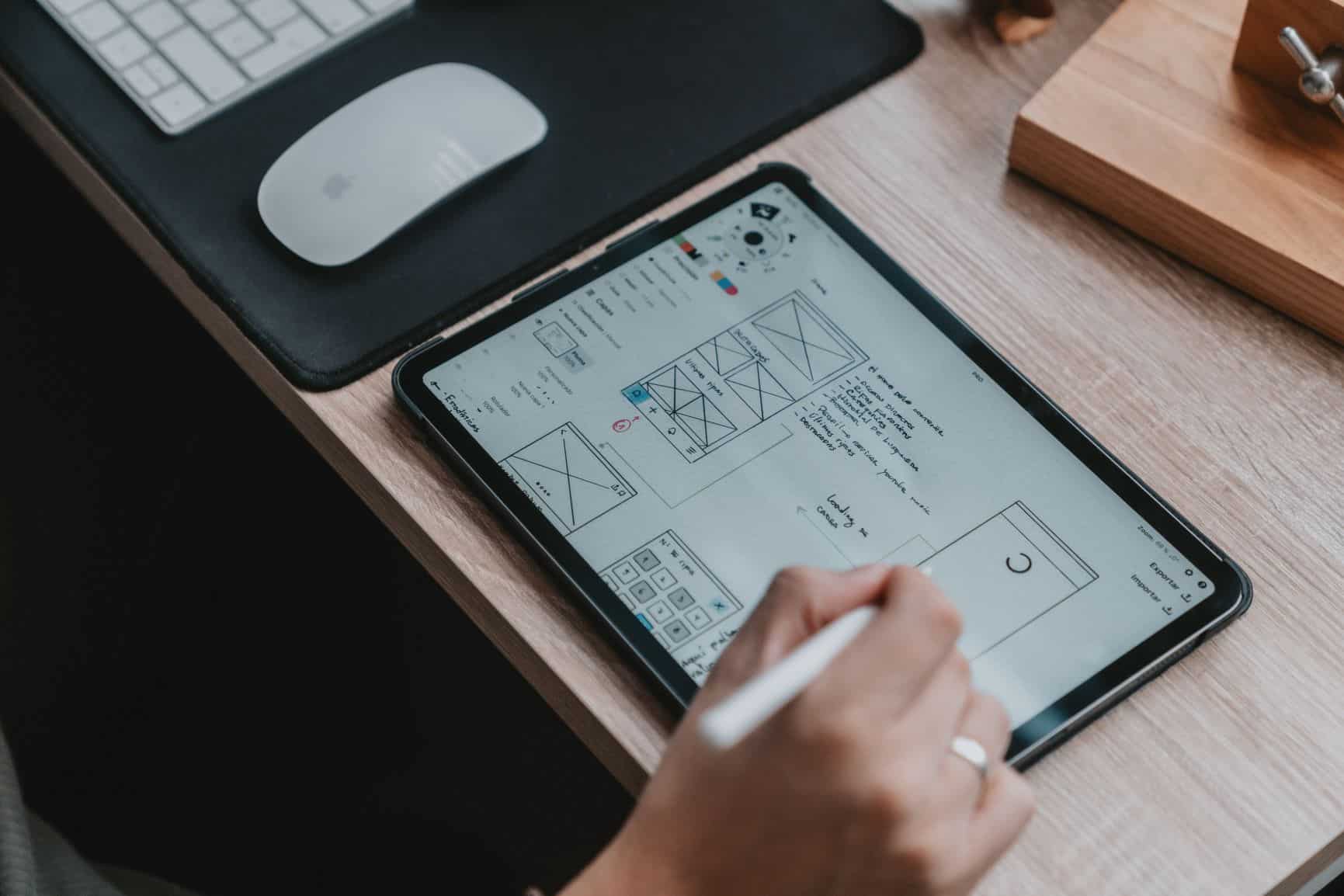 A designer works on their UX design by building wireframes on a tablet for a new website. 