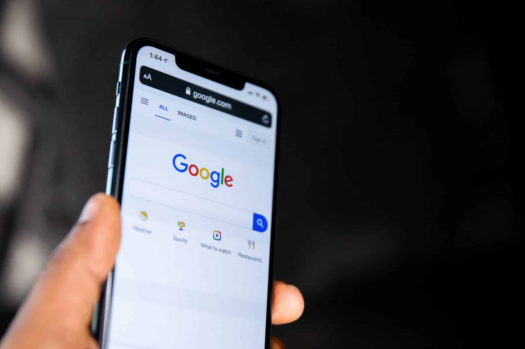 A smartphone screen with the Google homepage and search bar on the screen.