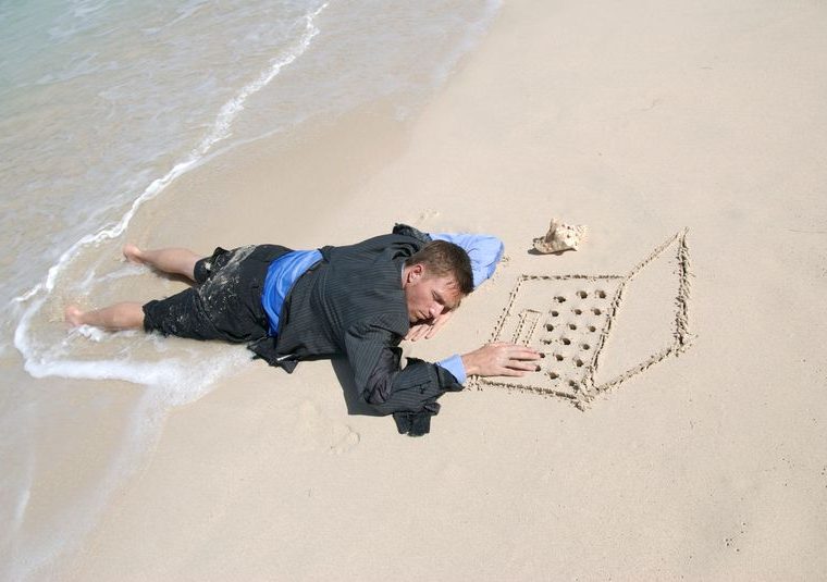 Man stranded on beach drawing laptop in sand to represent struggles facing web design companies.