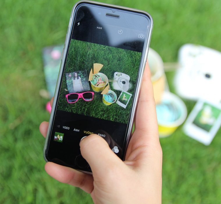 A user taking a photo of an assortment of products against a grassy background.