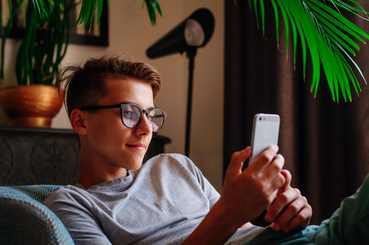 Young boy in glasses using phone. searching Google vs. TikTok