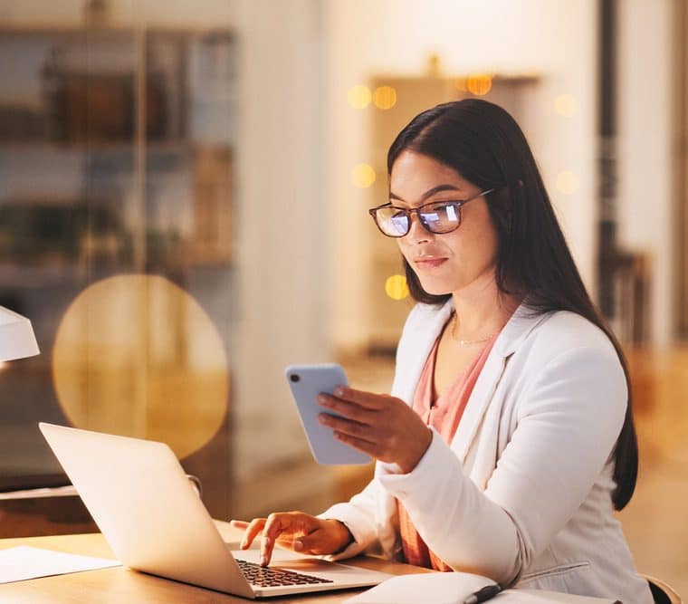 woman on computer looking at her phone and computer to learn more from website wiki