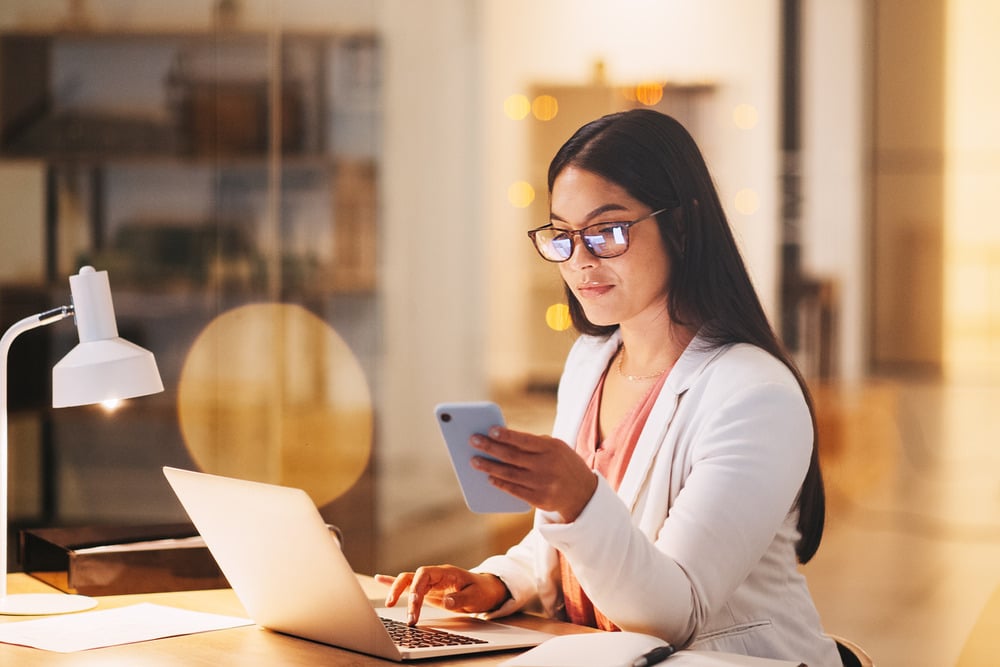 woman on computer looking at her phone and computer to learn more from website wiki