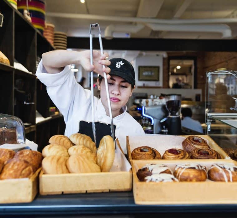 Woman picking a donut from a basket at a local shop