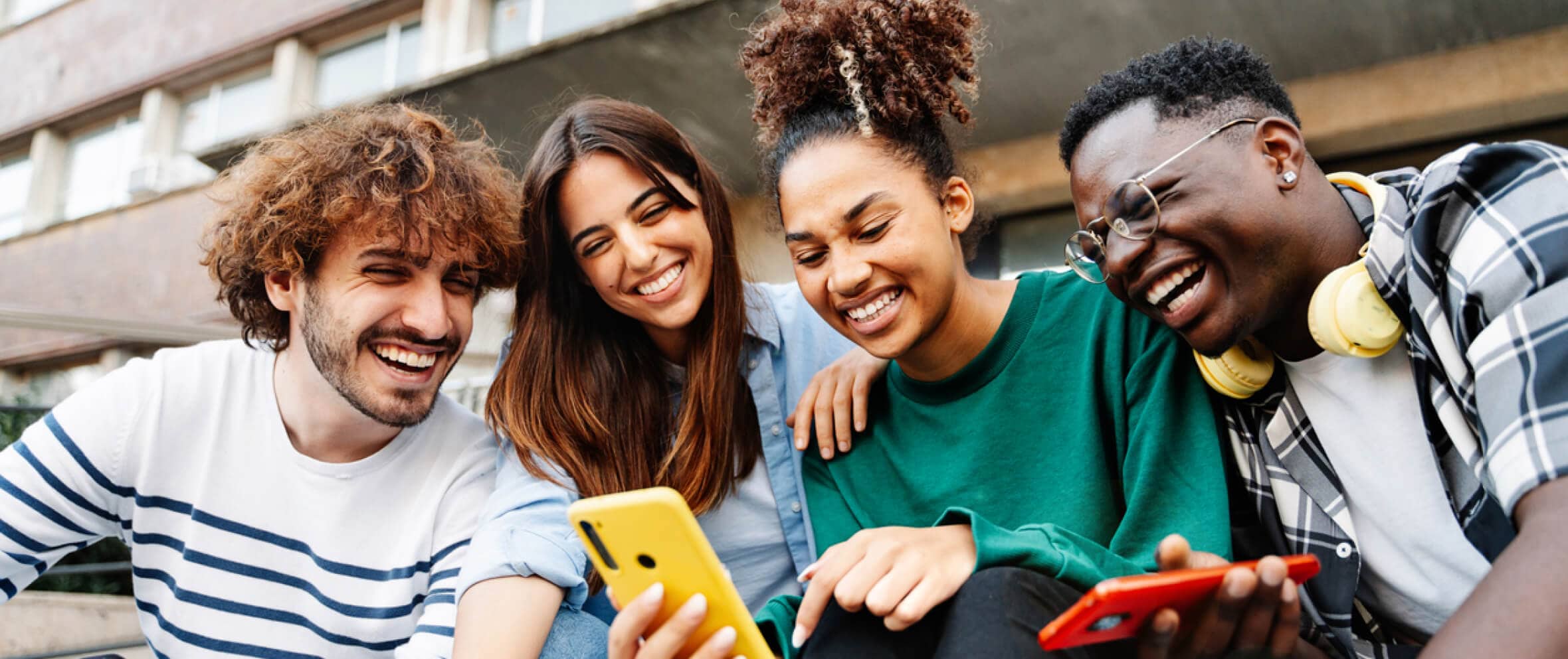 young adults smiling and looking at a smartphone