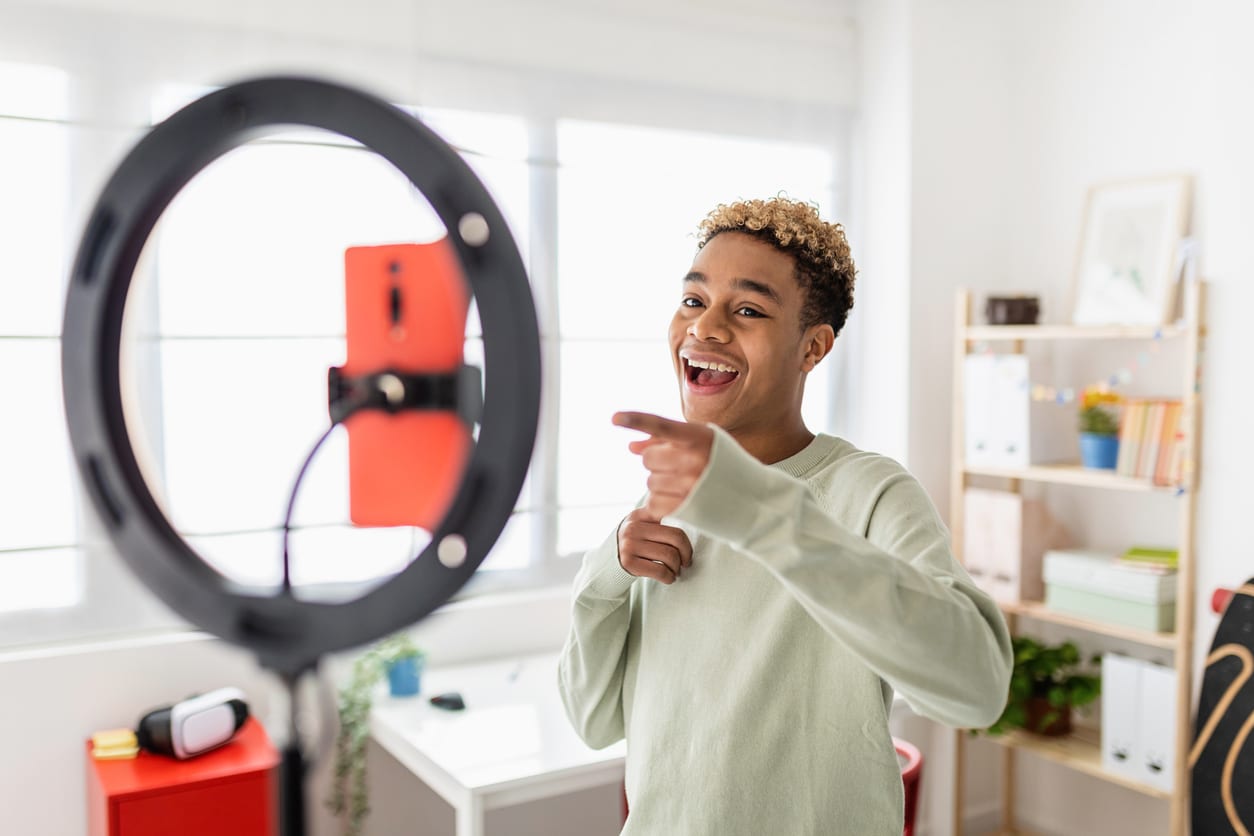 Young man in front of a ring camera phone holder recording himself participating in influencer marketing